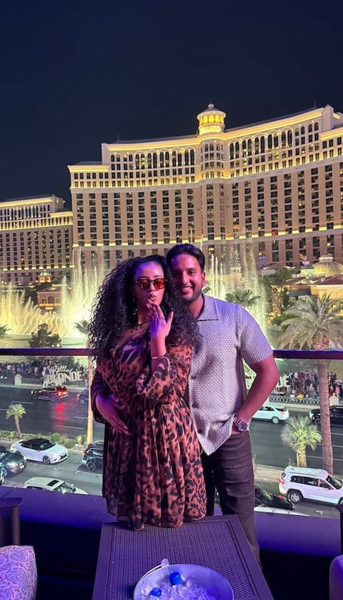 Couple posing together on a balcony overlooking the Bellagio fountains and Las Vegas hotels at night