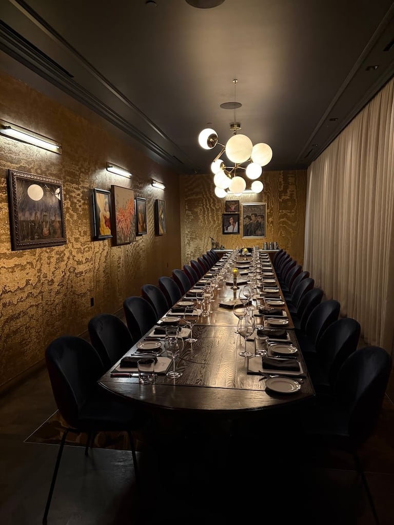 Elegant private dining room with a long black table, black chairs, cork textured walls, modern lighting fixtures, and formal place settings.