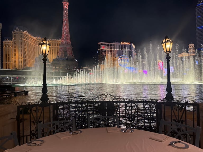 Night view of illuminated fountains with Eiffel Tower replica and vintage street lamps in Las Vegas