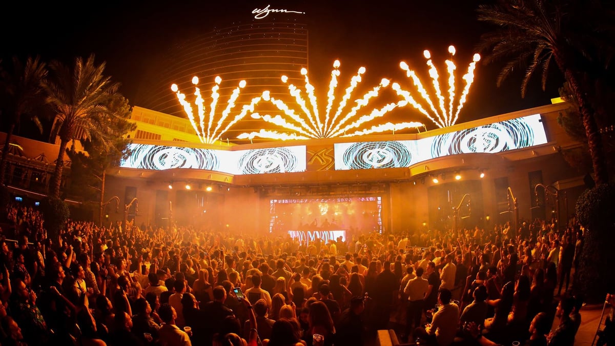 Large crowd at a concert or music festival with golden stage lighting and LED displays above the audience