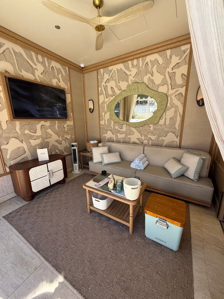 Modern living room with patterned wallpaper, gray sofa, wall-mounted TV, wooden coffee table, and decorative mirror.