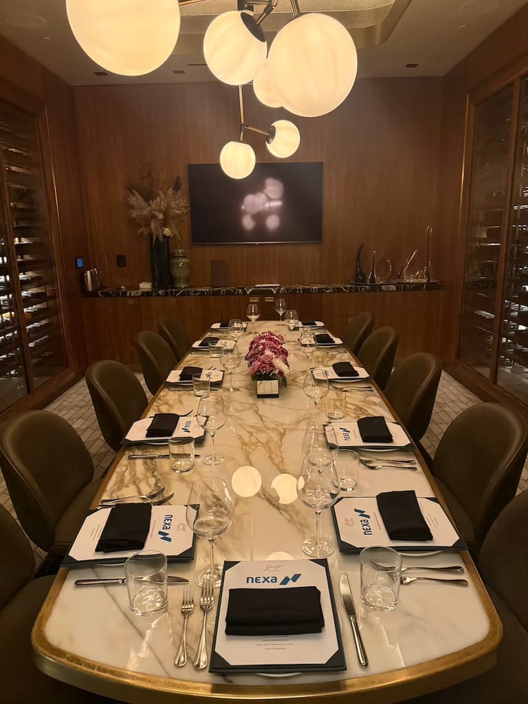 Elegant marble dining table set for a formal business dinner with place settings, glassware, and modern pendant lighting overhead