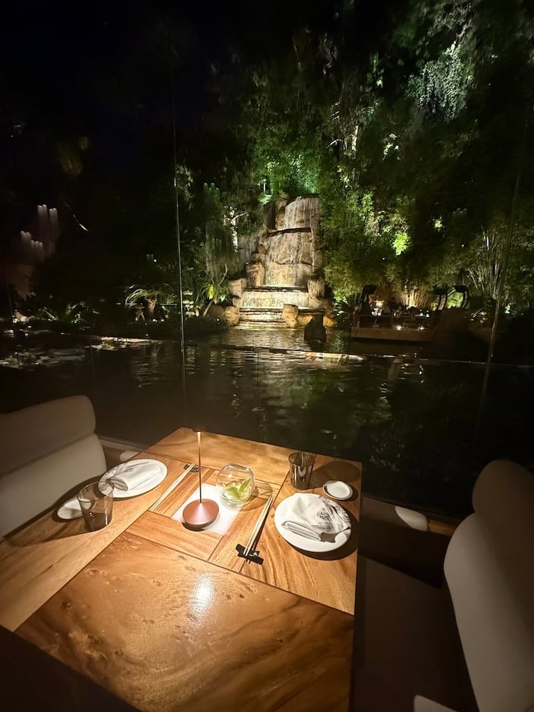 Romantic dinner table set on a boat with illuminated ancient ruins reflected in water at night